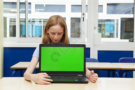 现代的学童浓度小天主教女孩带着绿色屏幕的笔记本电脑图片