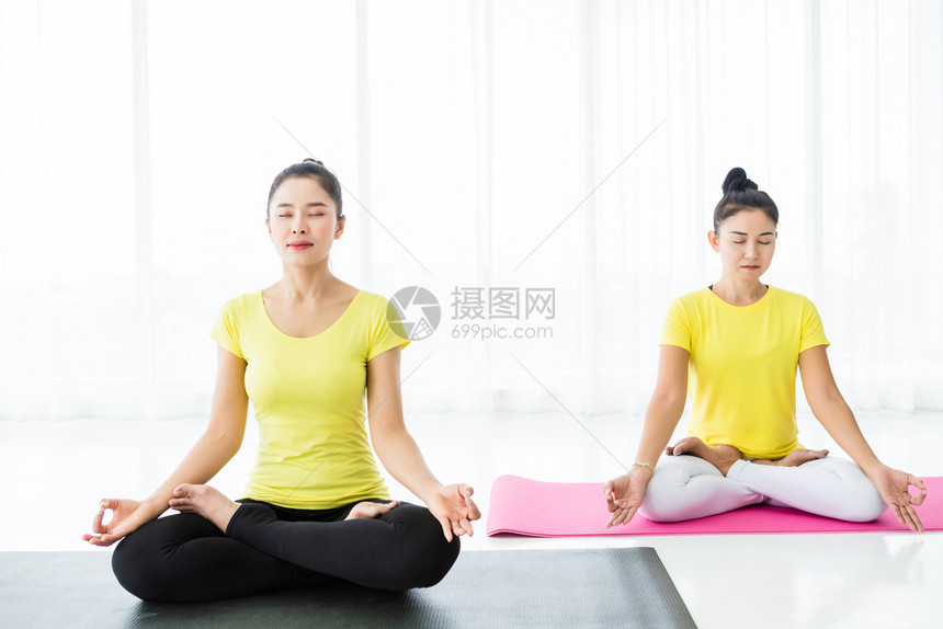 两名亚洲年轻妇女在健身房练习瑜伽穿黄色礼服或与训练员和实习者一起表演冥想健康生活方式和健康概念莲花伙伴年轻的图片