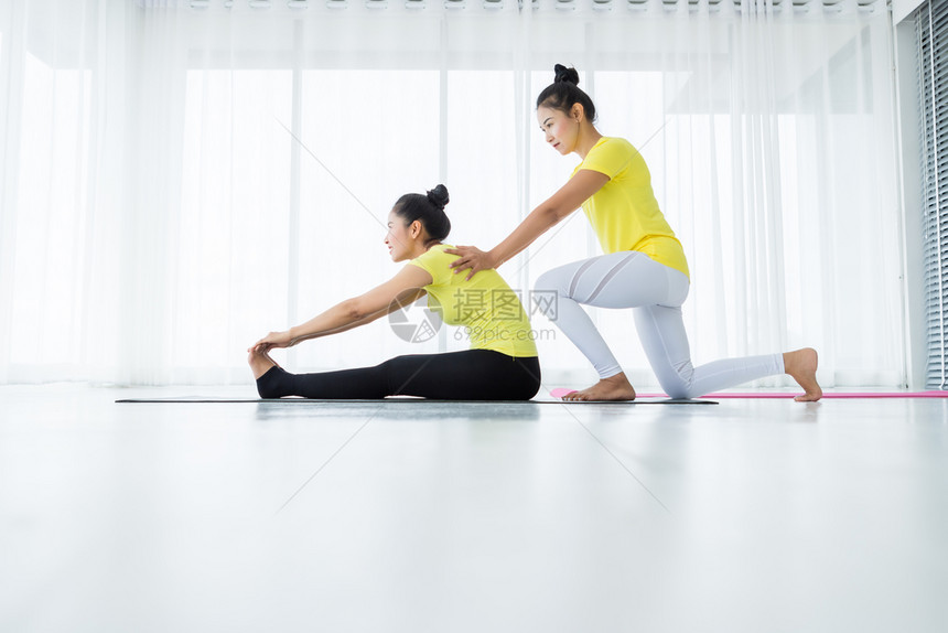 伙伴两名亚洲年轻妇女在健身房练习瑜伽穿黄色礼服或与训练员和实习者一起表演冥想健康生活方式和健康概念活动美丽的图片