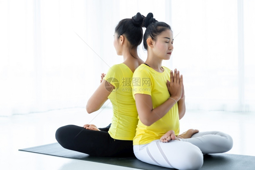 普拉提体式一种两名亚洲年轻妇女在健身房练习瑜伽穿黄色礼服或与训练员和实习者一起表演冥想健康生活方式和健康概念图片