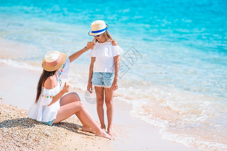 沙滩上给女儿涂防晒的母亲背景图片