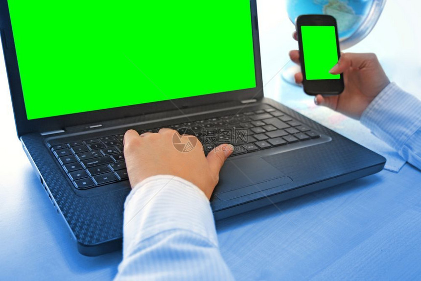 联系在职的女办公室用笔记本电脑和智能话工作时手握绿色屏幕个人电脑图片