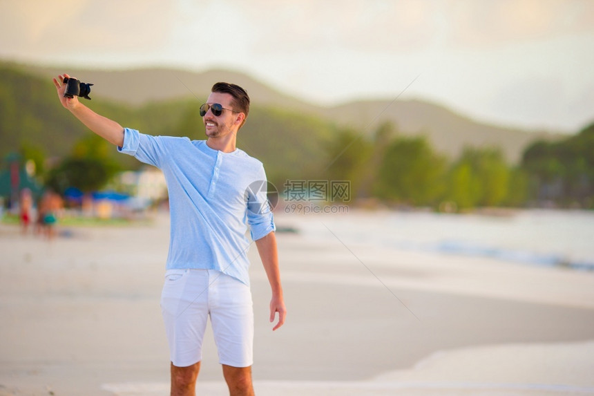 美丽的年轻男子在热带海滩上自己拍照美丽的年轻男子在热带海滩上自己拍摄的相片她假期闲暇图片