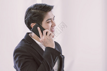 快乐的成功一个亚洲商人在正式诉讼通过手机交谈电话坦率图片