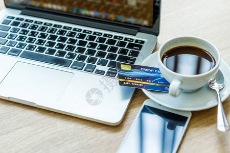 技术桌子沟通笔记本电脑智能手机和木背景咖啡杯的信用卡在线银行概念图片