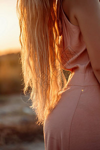 户外美丽身着粉红色裙子在日落背景的荒地上裸露在一片荒野中时髦图片