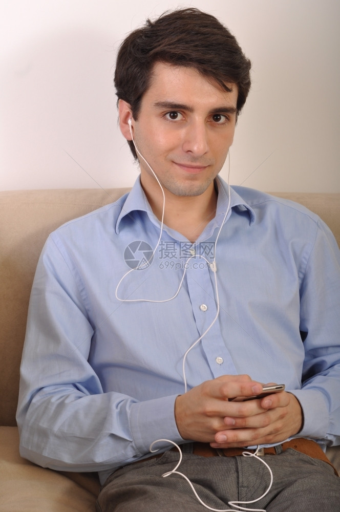 内部的技术耳机在沙发上听音乐的有吸引力年轻人图片