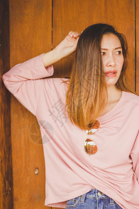 女士肖像一名身穿粉红衬衫站在木门对面的妇女时髦图片