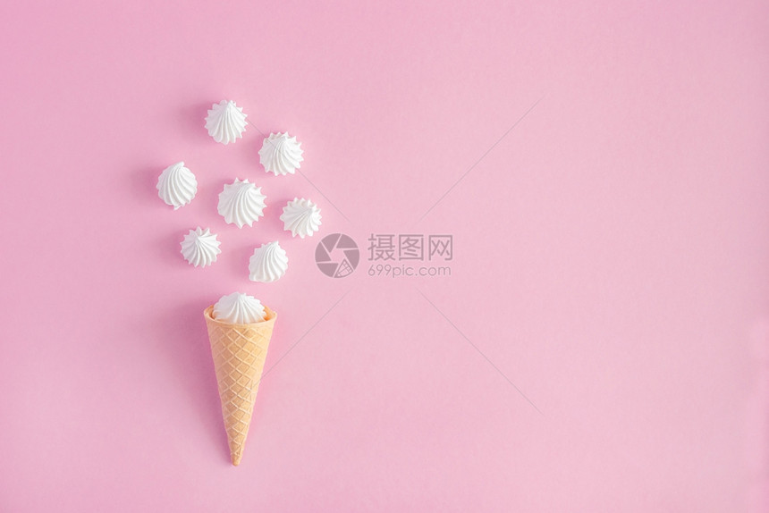 粉彩薄饼冰淇淋甜筒粉红背景上散落的白扭曲蛋时尚锥体图片