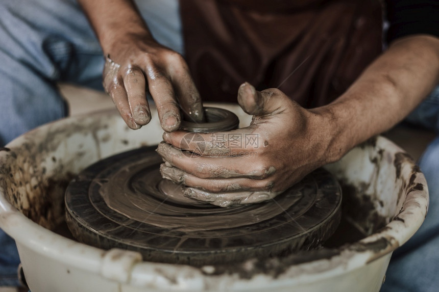 工艺泥术家在陶器车轮上工作的匠手掌选择焦点图片