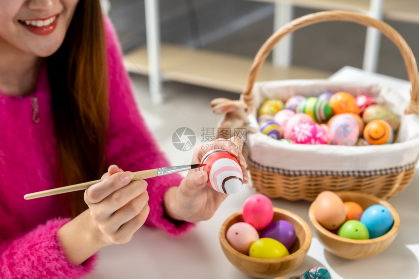 保持复活节的概念带着兔子耳朵的亚洲快乐年轻女披着兔子耳朵的青春少女为复活节画了鸡蛋在白衣室背景下可爱的孩子图片