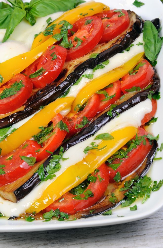 调味料含西红柿黄胡椒和切片莫扎里拉的烤茄子配给沙拉图片