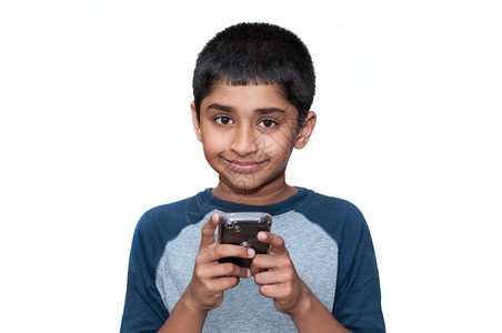 电话一个英俊的印地安小孩玩手机游戏愉快精力充沛图片