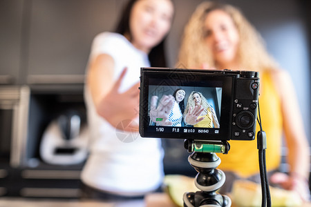网络女孩和白在厨房为博客拍摄一个视频影片青少年图片