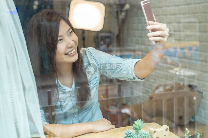亚洲女商人在现代咖啡店或工作场所共同空间现代办公室生活方式和休闲概念中以幸福的方式自拍移动手机照片图片