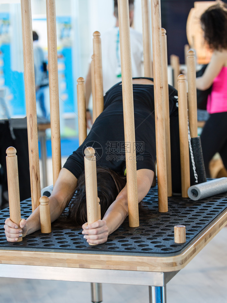 女孩在带有可移动木柱的穿孔桌子上进行健身锻炼女孩在带有可移动木柱的穿孔桌子上进行健身锻炼康活动白种人图片