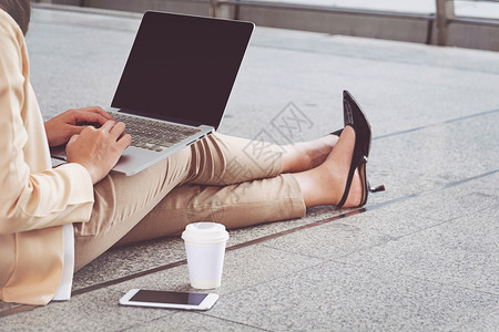 公司的穿着高跟鞋女商人坐在地板上大腿有电脑手键盘图片