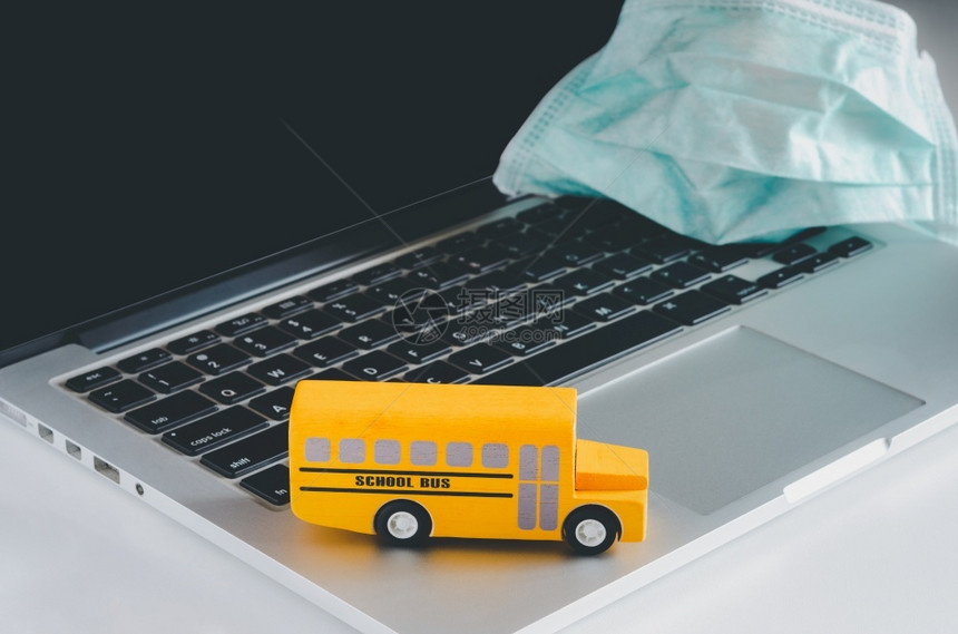 在隔离期间用膝上型计算机带医疗面罩的黄色校车返回学在线教育概念隔离期间笔记本工具黄色的图片