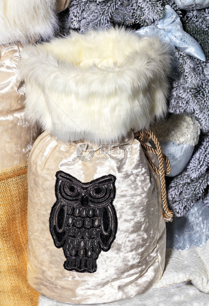 新年大米亮闪的礼品袋上面有皮衣领和灰色刺绣猫头鹰在装饰的灰色圣诞树下新年大米亮的礼品袋圣诞树下有皮衣领解雇冬天明亮的图片