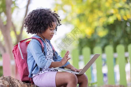 一个可爱的卷发女孩使用笔记本电脑视频话和朋友头发坦率专注图片