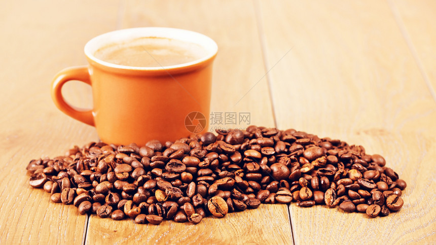 橡木棕色的咖啡杯和豆木制桌上的咖啡杯在木制桌边的咖啡杯因图片