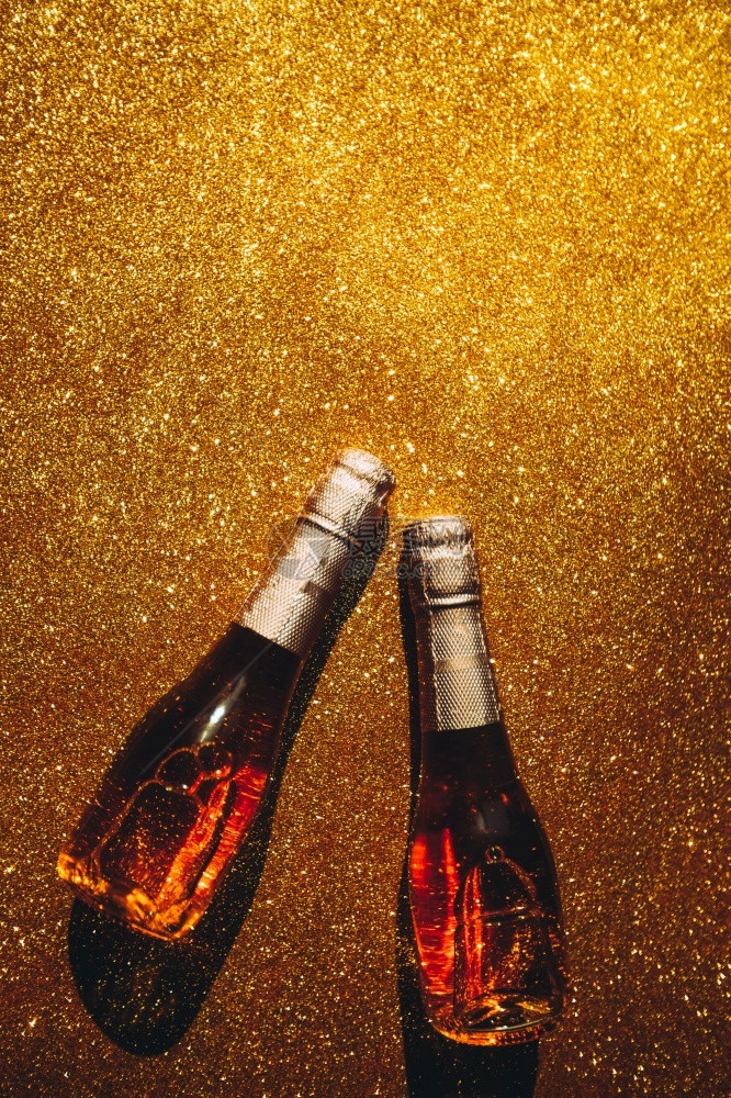 聚会圣诞或新年的配制盛满玫瑰香槟的瓶子在金光闪亮背景上以黑暗阴影为顶端风景庆祝平坦的世俗派对创意概念快乐的灯图片