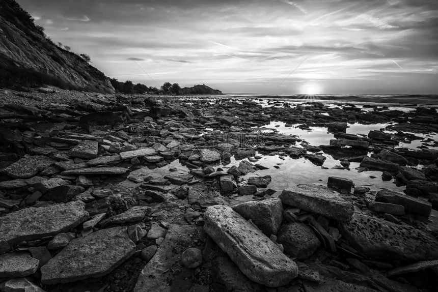 一个惊人的日出在岩石海岸面上黑白两色华丽的风景优美图片