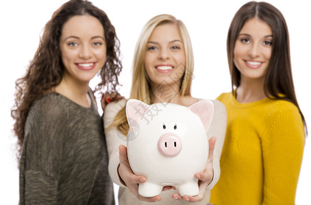 3名少女持有小猪银行的演播室肖像幸福钱微笑图片
