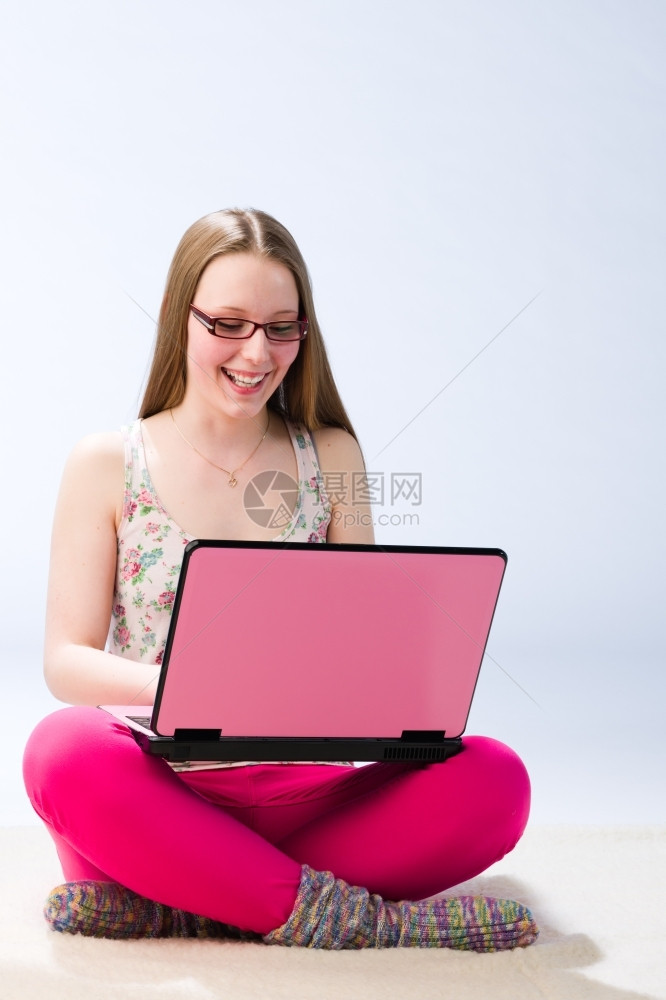 女随意的一个年轻美丽女孩微笑并使用笔记本电脑快乐图片