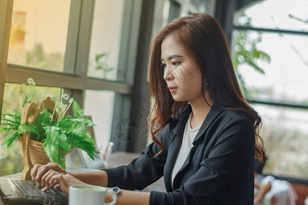 职业在的年轻亚洲商业妇女使用笔记本进行工作鼓动和软焦点图片