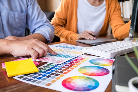 两个同事的创意图形设计师从事颜色选择和在工作场所图案平板上绘画工作两名同事人们趋势建筑师背景图片