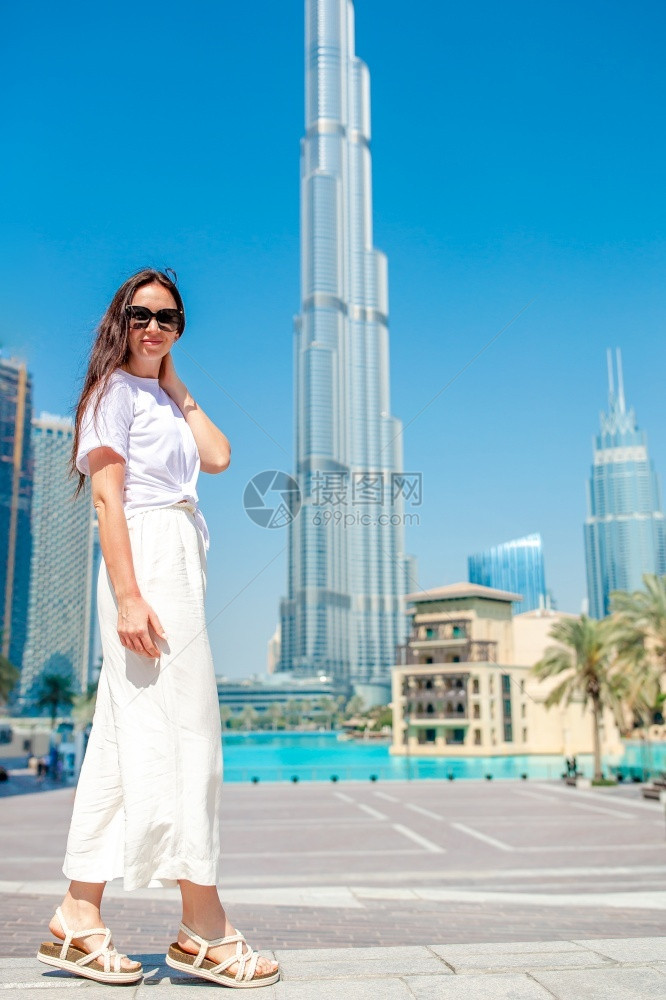 阿联酋建筑学吸引人的美丽女在迪拜行走的肖像与摩天大楼背景色中从后面欢乐妇女身走在迪拜其背景是摩天大楼图片