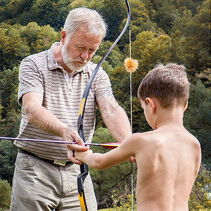 玩射击年长男人教小孩怎么把箭放弓中瞄准学习背景