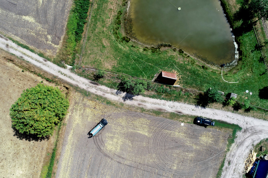 收成稻草获垂直空中观察在采伐田和草地旁边的一条道路上方有一个小马匹在池塘前进行捕捞图片