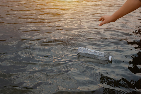 妇女手拿起用废塑料瓶装在运河水中的废塑料瓶垃圾用过的干燥图片