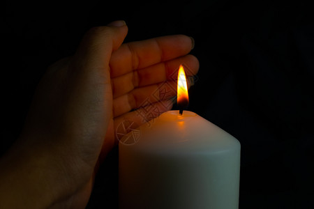精神手保护蜡烛的灯光防止黑底暗中的风警卫吹图片