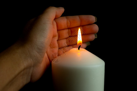 阴影手保护蜡烛的灯光防止黑底暗中的风祈祷熄灭图片