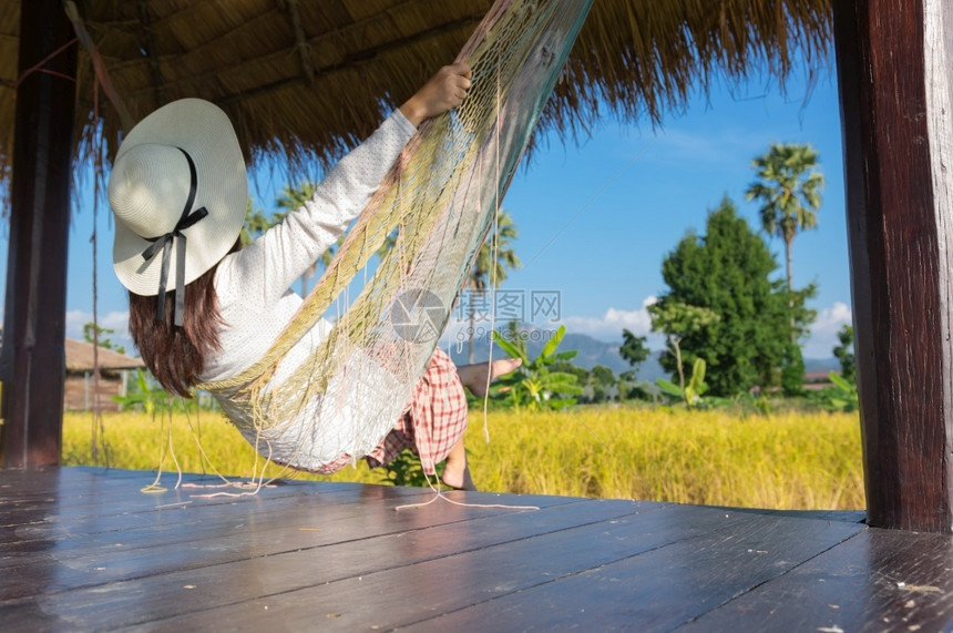 太阳清晨在度假胜地的摇摆或吊床上着放松的年轻女孩在吊床上着放松热带肖像图片