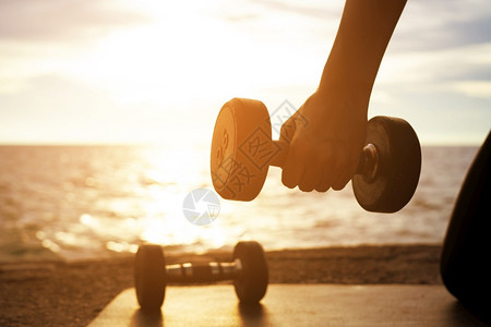 户外在日落时海边保持哑铃锻炼健康的概念和锻炼过程库存积极的图片