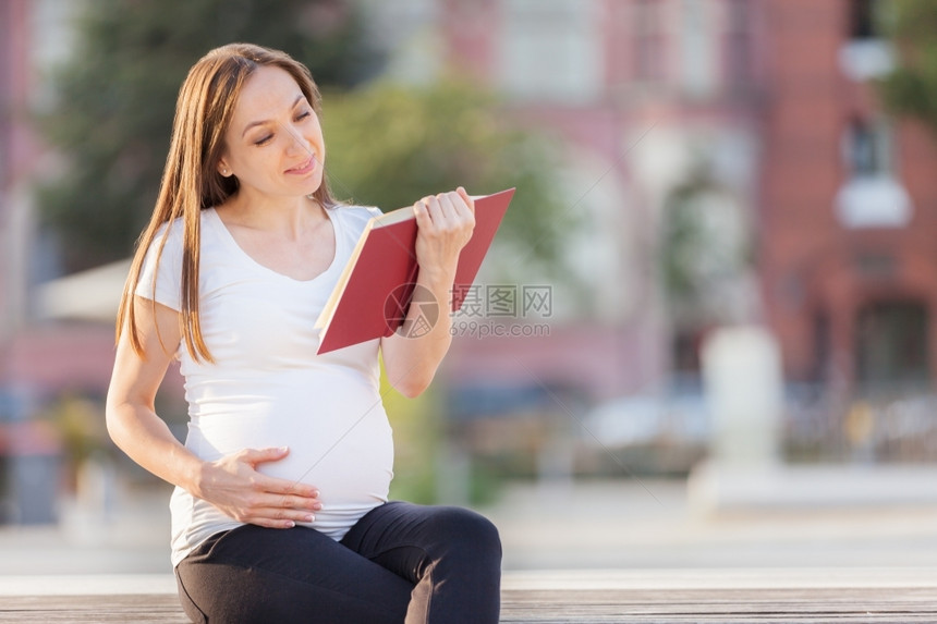 城市CaucasianBrunette孕妇在长椅上阅读这本书的照片白种人随意的图片