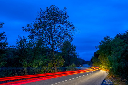 自然照亮夜间森林路上的长绕风道尾灰丝小路和深夜森林上的末光轨迹灯背景图片