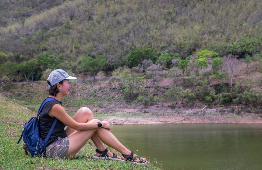 河外部在湖岸边坐和享受美好景色平时刻的年轻青女侧面观其背景为假日旅行概念休息和享受生活方式选择重点等山脉分布在上一种图片