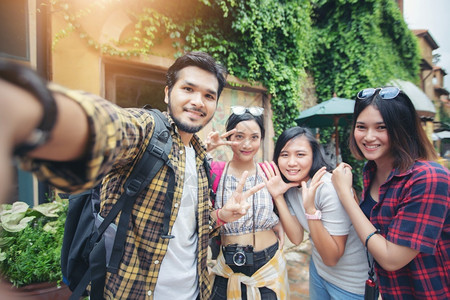 自游自在乐趣亚洲集团年轻人与朋友背包一起散步快乐的朋友正在拍摄照片和自在假日概念旅行上时间比较慢而喜悦的朋友们在拍照和自户外背景
