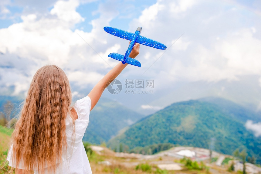 保持顶峰云长发女孩在户外玩得开心快乐的小女孩带着玩具飞机在山上手握着玩具飞机图片