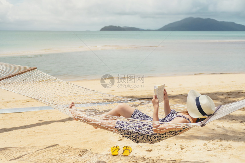麦女在节假日暑自由时间阅读关于吊床上海滩的书籍休息躺着图片