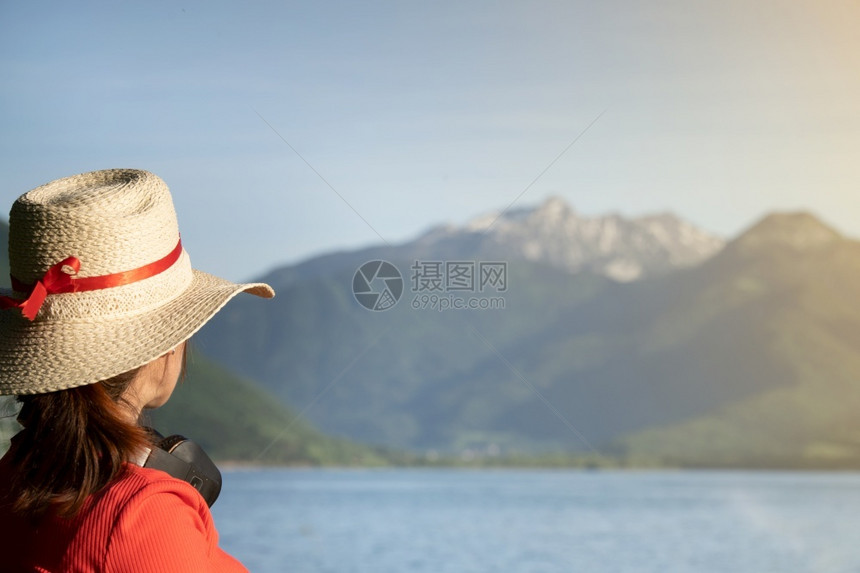 女孩带着耳机戴小帽子穿红色礼服的女孩仰望着湖边的山峰女阿尔卑斯山独自的图片