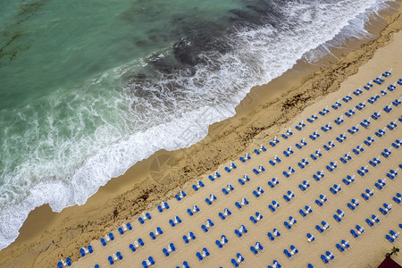 从无人驾驶飞机空中观视海滩带白雨伞休息椅和绿海无人机浪岸图片