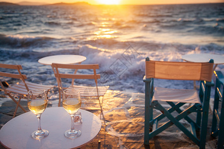 喝饮料的太阳饮料海边餐桌的厅日落夏假期时喝白葡萄酒桌子晚餐背景