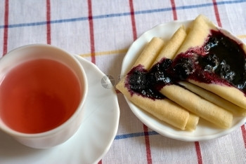 绉纱美味的棕色煎饼加果酱和一杯红茶的煎饼图片