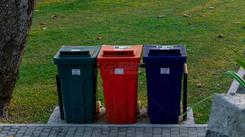 加勒堡公园的有色垃圾集装箱排成一绿色用于有机物橙子桶用于塑料聚乙烯蓝色垃圾箱用于纸张废物处理草地蓝色的污染图片
